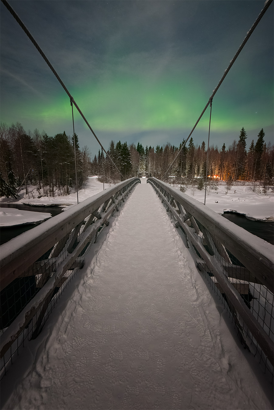 Photo The Bridge montrant un pont en bois sous une aurore boréale en Laponie finlandaise en 2025.