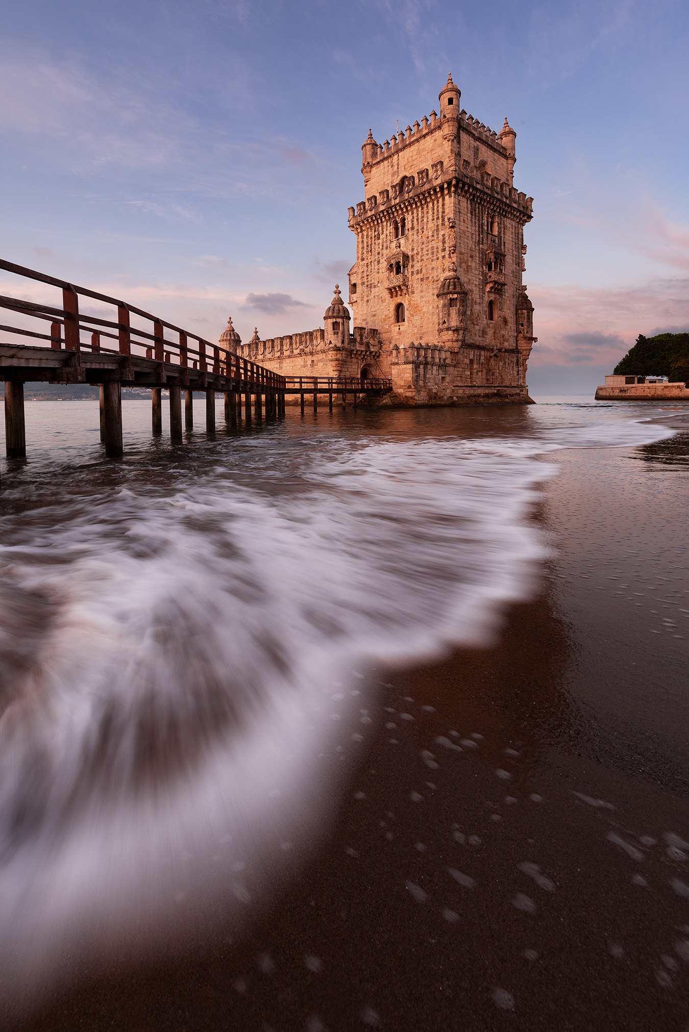 Photo de la tour de Belém avec une vague au premier plan illustrant l’utilisation du mouvement pour construire une composition en photographie