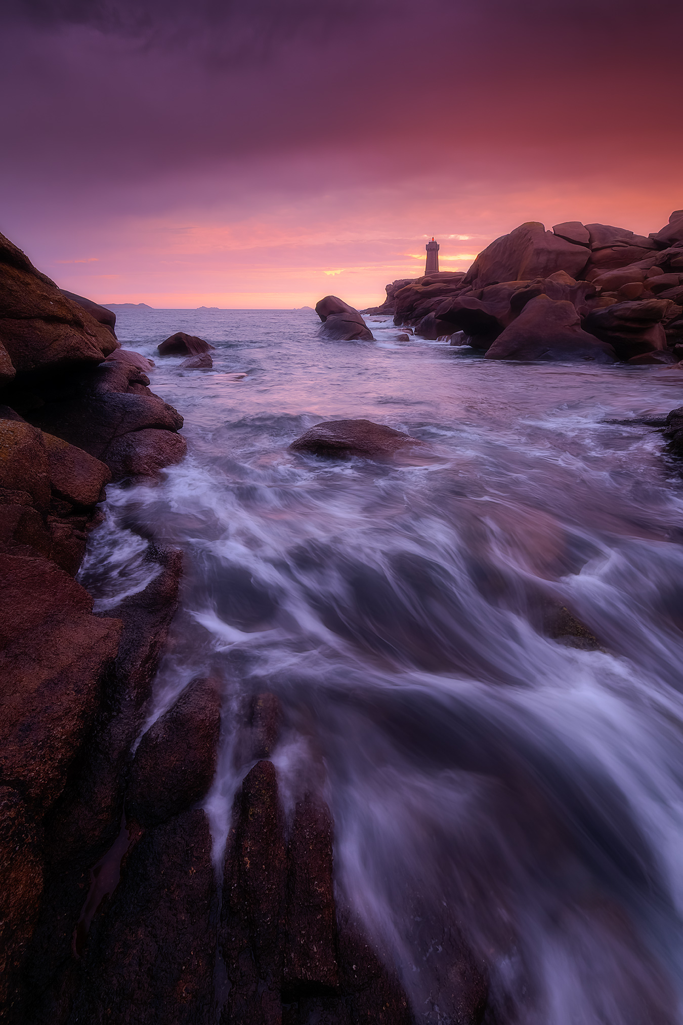 Féerie Pose longue sur la côte de granit rose avec le phare de Mean Ruz et une vague en mouvement au premier plan à l’heure bleue.