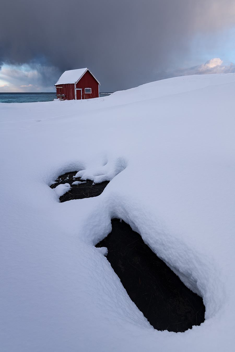 Cabane rouge dans un paysage enneigé avec une ligne naturelle guidant le regard à travers la composition photographique
