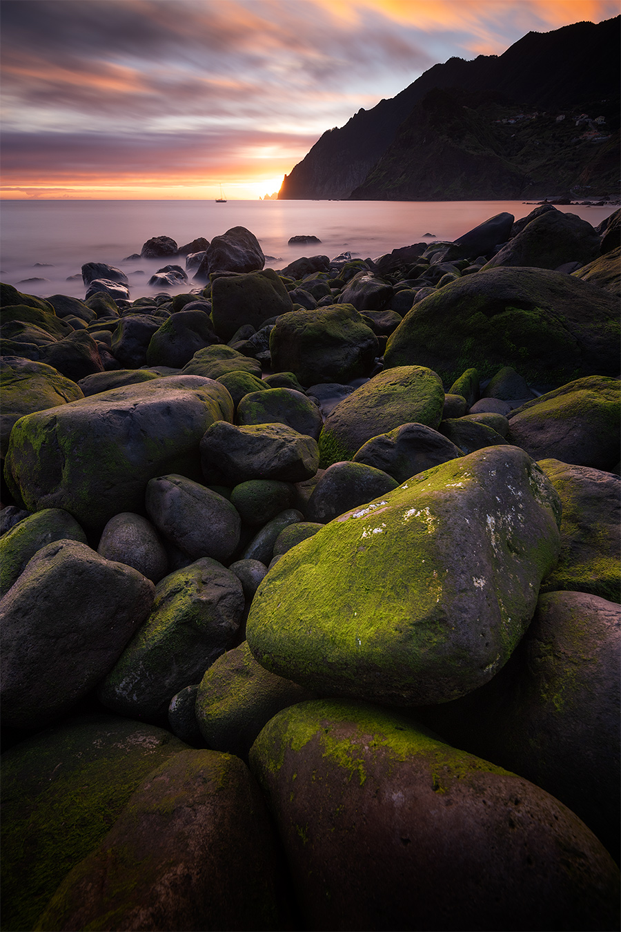 Combiner focus stacking et bracketing d'exposition Plage rocheuse au coucher du soleil avec un premier plan de rochers moussus photographiée en focus stacking et bracketing d'exposition.