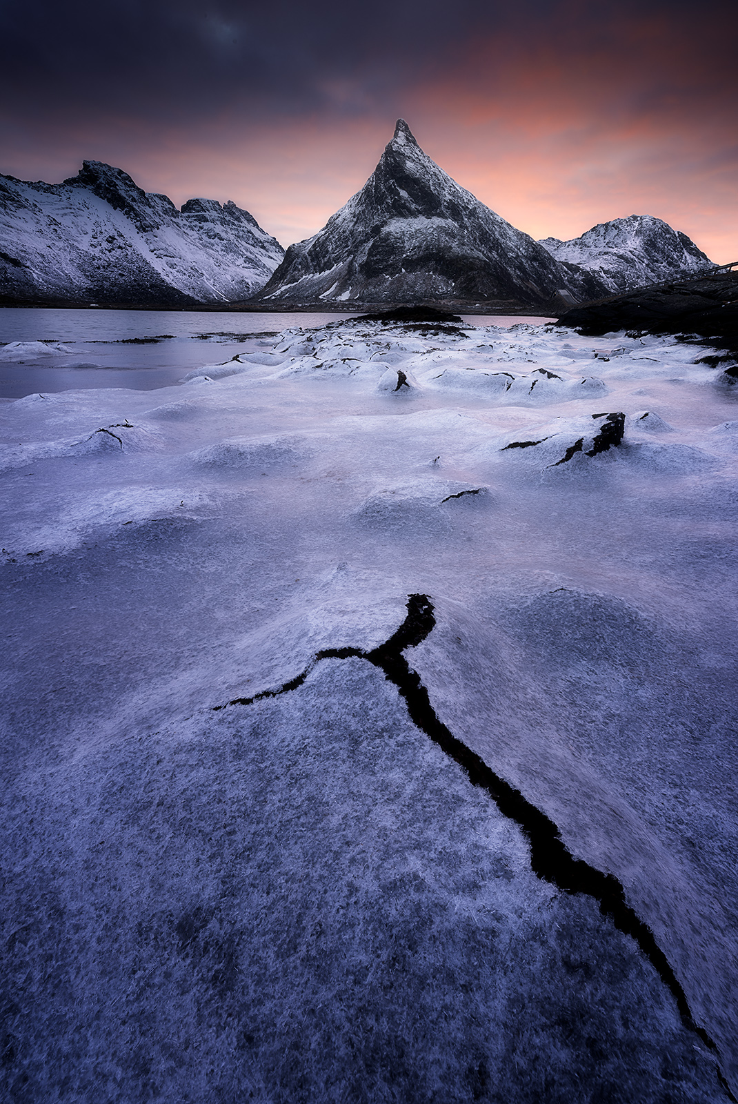 Photographie grand angle Lofoten - glace craquelée au premier plan et montagne enneigée en arrière-plan