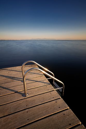 Se jeter à l'eau. Un ponton face à l'immensité, Aude, Occitanie. Échelle de baignade métallique au bout d'un ponton en bois, eau calme, Aude, Occitanie.