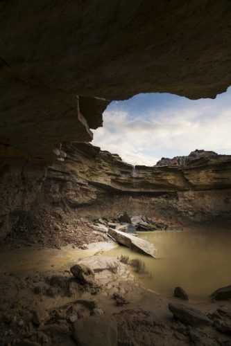 Point d'eau sous une voûte rocheuse évoquant une grotte, désert des Bardenas Reales, Navarre, Espagne.