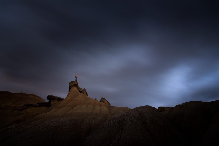 Silhouette au sommet d'une formation rocheuse de nuit, désert des Bardenas Reales, Navarre, Espagne.