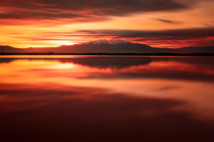 Embrasement. Coucher de soleil sur l'étang de Canet-en-Roussillon, avec le Canigó en fond. Coucher de soleil rouge orangé sur l'étang de Canet-en-Roussillon, silhouette du Canigó en fond.