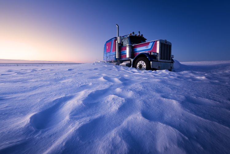 Camion Peterbilt bleu et rouge évoquant Optimus Prime, bloqué dans la neige au lever du soleil, Islande.
