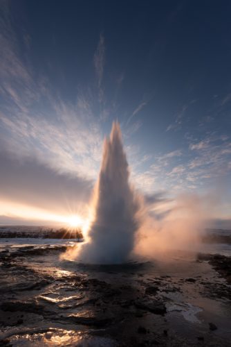 Éruption du geyser Strokkur au lever du soleil, région du Geysir, Islande.