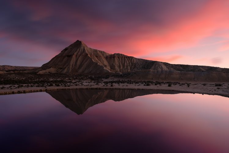 Formation rocheuse désertique reflétée dans l'eau au coucher du soleil, désert des Bardenas Reales, Navarre, Espagne.