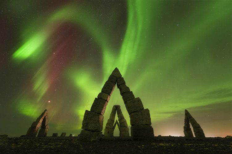 Arches en pierre de l'Arctic Henge sous une aurore boréale verte et rouge, Raufarhöfn, Islande.