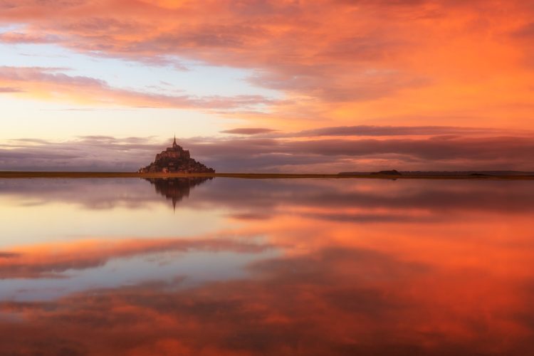 Mont-Saint-Michel reflété dans l'eau au coucher du soleil, Manche, Normandie.