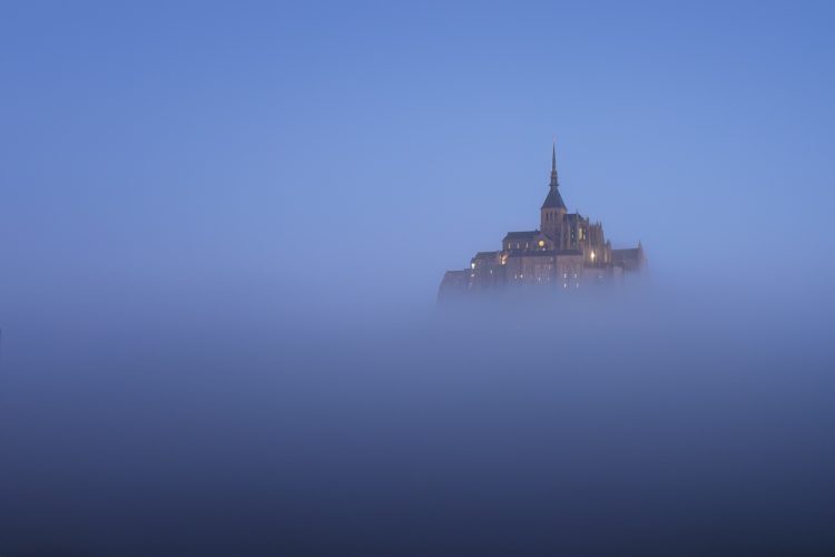 Mont-Saint-Michel émergeant de la brume à l'heure bleue, Manche, Normandie.
