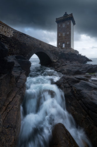 Vagues déferlant sur les rochers sous le phare de Kermorvan, Bretagne.