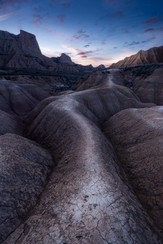 Chemin sinueux entre les reliefs érodés au lever du soleil, désert des Bardenas Reales, Navarre, Espagne.