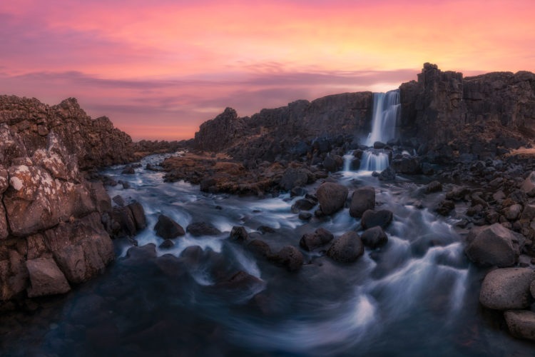 Cascade d'Öxarárfoss se déversant entre les falaises basaltiques, eau tourbillonnante au premier plan, parc national de Þingvellir, Islande.