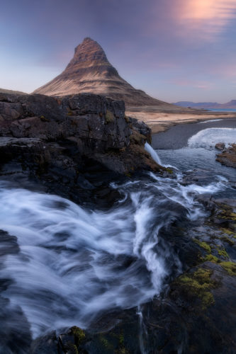Rivière tumultueuse jaillissant d'une cascade, silhouette du Kirkjufell au coucher du soleil, Grundarfjörður, Islande.