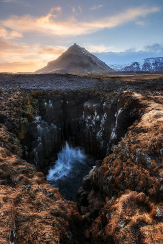 Vagues s'engouffrant dans la faille de Músagjá, montagne Stapafell en arrière-plan, coucher de soleil, Islande.